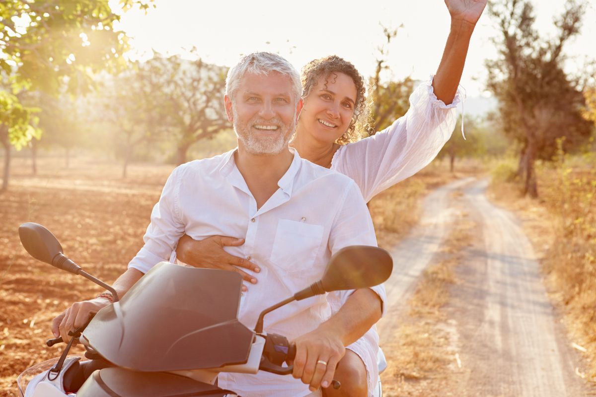 Adventurous middle aged couple outdoors on motorbike