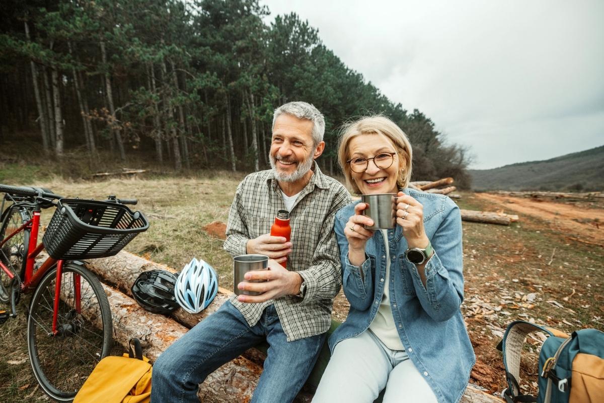 Mature cycling couple enjoying coffee break in nature Mature cycling couple enjoying coffee break in nature