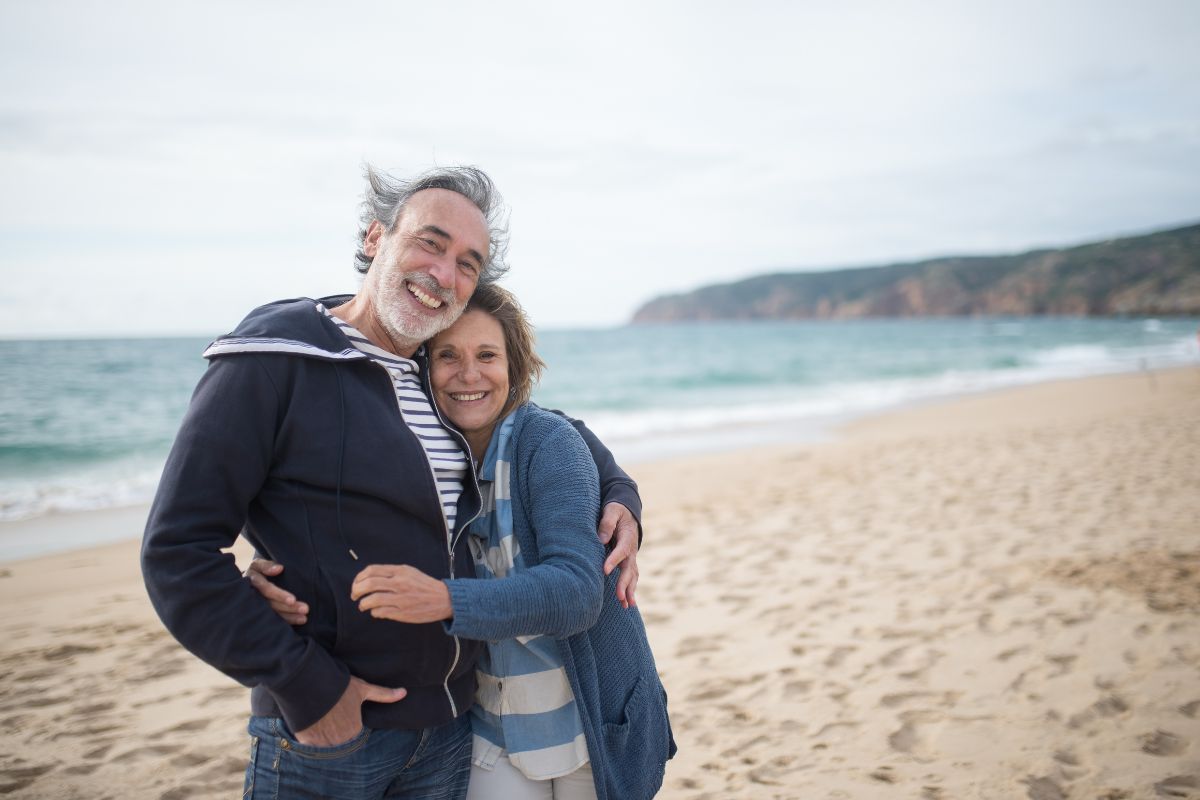 Middle aged couple hugging and smiling on the beach
