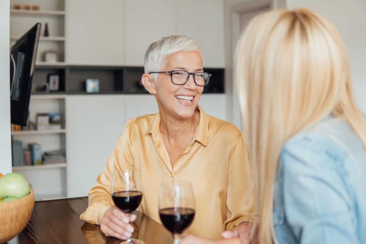 Older woman drinking red wine with younger woman